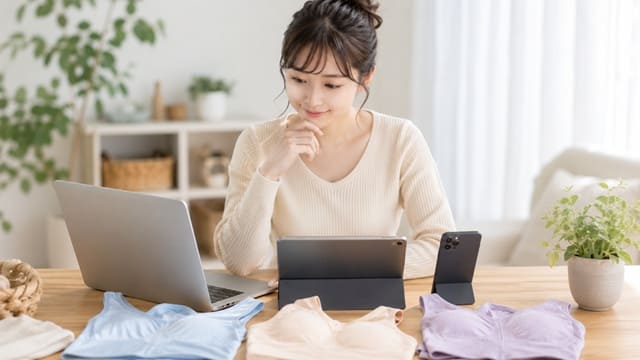 ノンワイヤーブラを前にパソコンやスマートフォンで価格や購入先を比較する女性の様子。ジニエブラエアーの最安値や正規販売店選びをイメージした写真